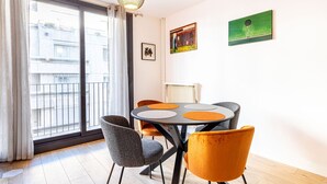 Una sala de estar moderna con una mesa redonda, dos sillas, un radiador y obras de arte en las paredes.