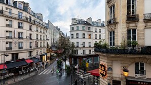A street view with buildings, a café named Café Lola, and a restaurant named Le Buc. - GuestReady - Modern apartment in a prime location (Paris)
