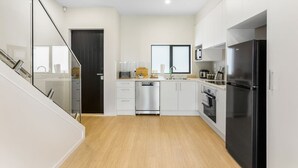 Eine moderne Küche mit weißen Schränken, Edelstahlgeräten und Holzboden.