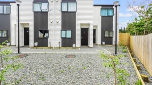 Ein modernes Wohngebäude mit zwei Etagen, einer symmetrischen Fassade, großen Fenstern und einer Schotterauffahrt.