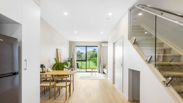 Eine moderne Küche mit Essbereich, einer Treppe mit Glastrennwand und Blick ins Freie.