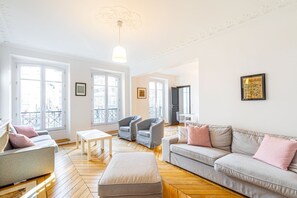 Ein geräumiges Wohnzimmer mit einer Couch, Sesseln, einem Tisch und einem Balkon.