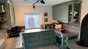 Une cuisine moderne avec des meubles de couleur turquoise, un four encastré et un poêle en pierre.