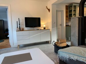 Una sala de estar moderna con televisor de pantalla plana, un mueble blanco, una chimenea y un rincón de estar acogedor.