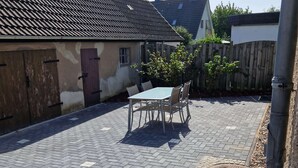 Un espace extérieur aménagé avec une table et des chaises, un sol en briques et une clôture en bois.