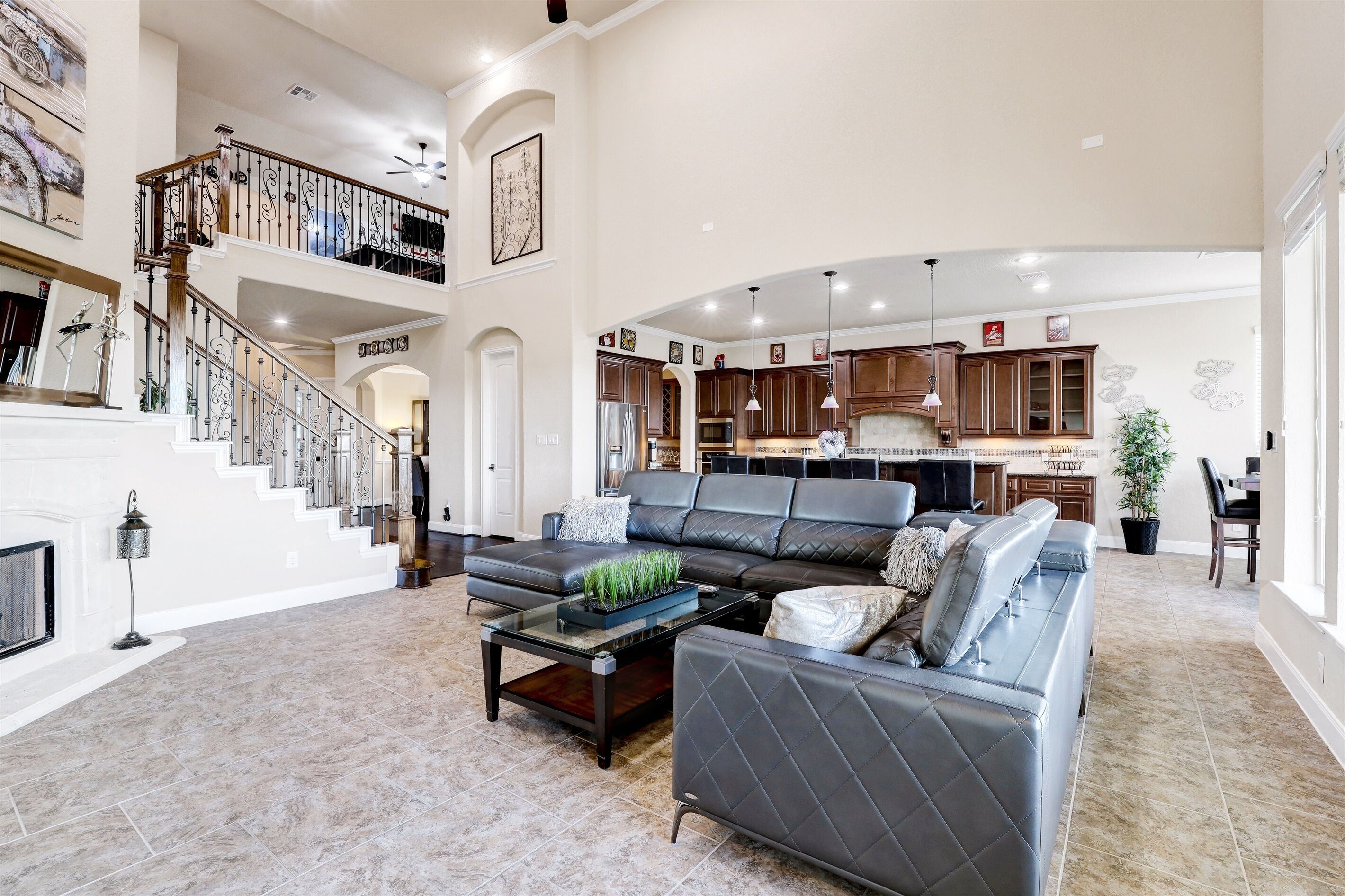 A spacious living area with a large sectional sofa, a fireplace, and a staircase leading to an upper level.