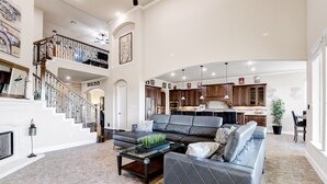 A spacious living area with a large sectional sofa, a fireplace, and a staircase leading to an upper level. - The Views are for Miles! (San Antonio)