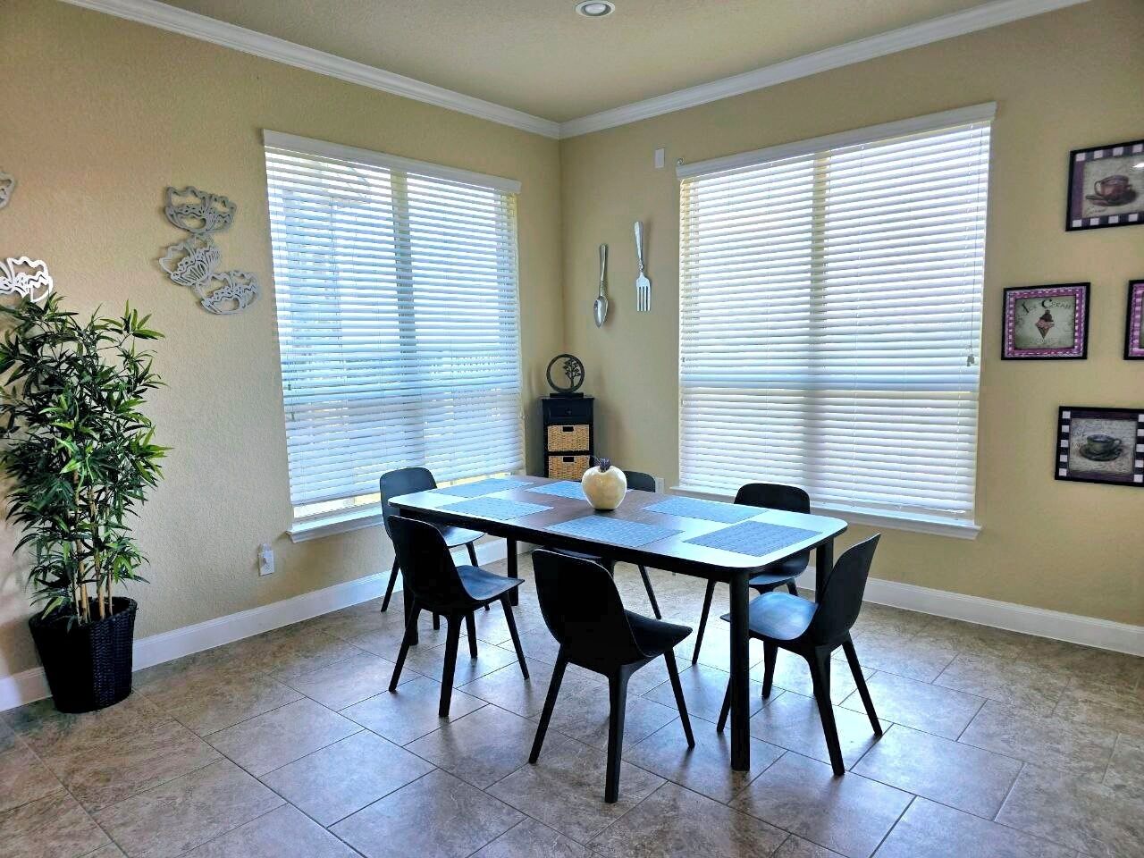 A dining area with a rectangular table, six chairs, and a potted plant.