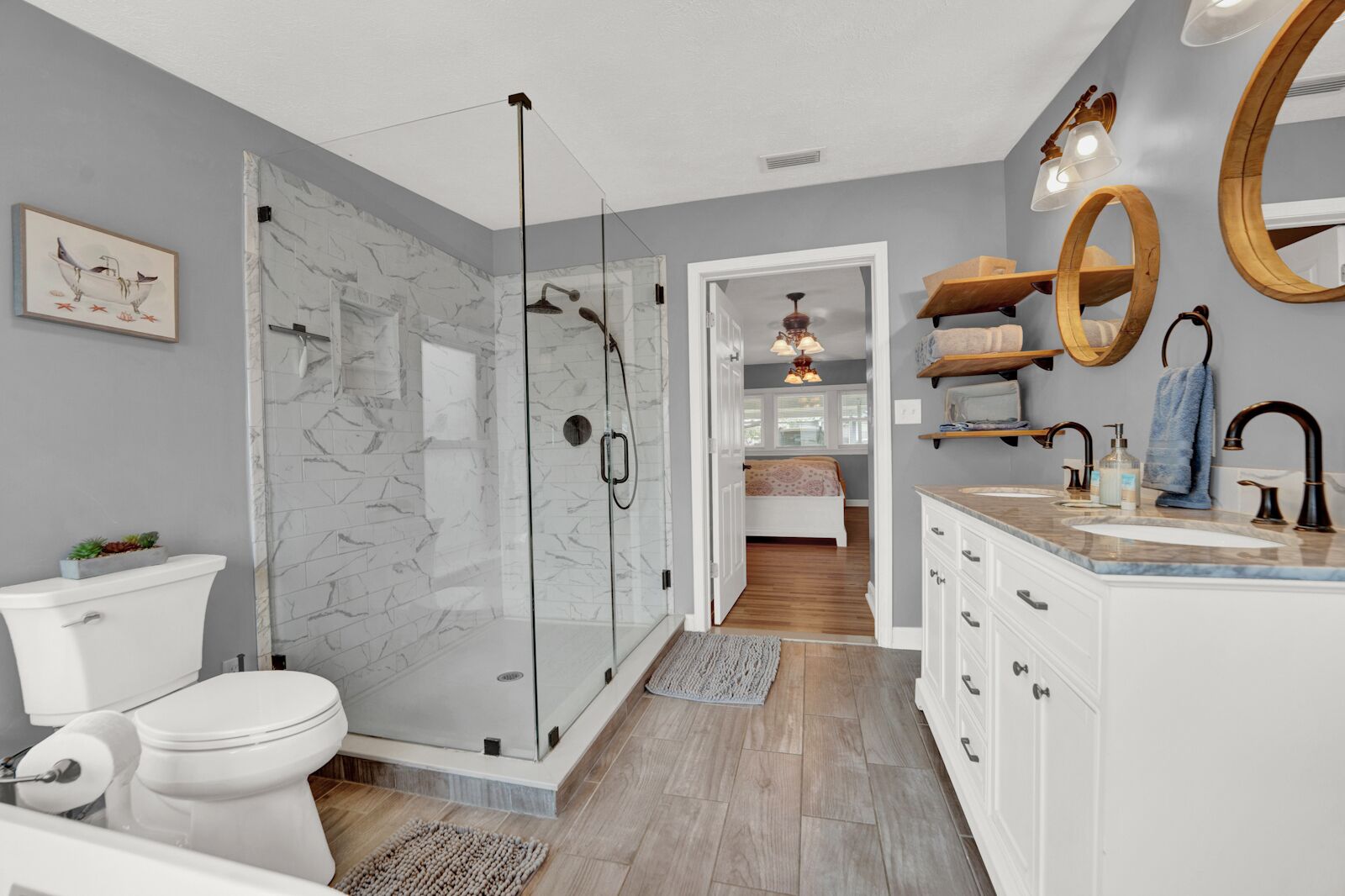 Une salle de bain moderne avec une douche à parois de verre, des toilettes blanches, un meuble-lavabo et un miroir.