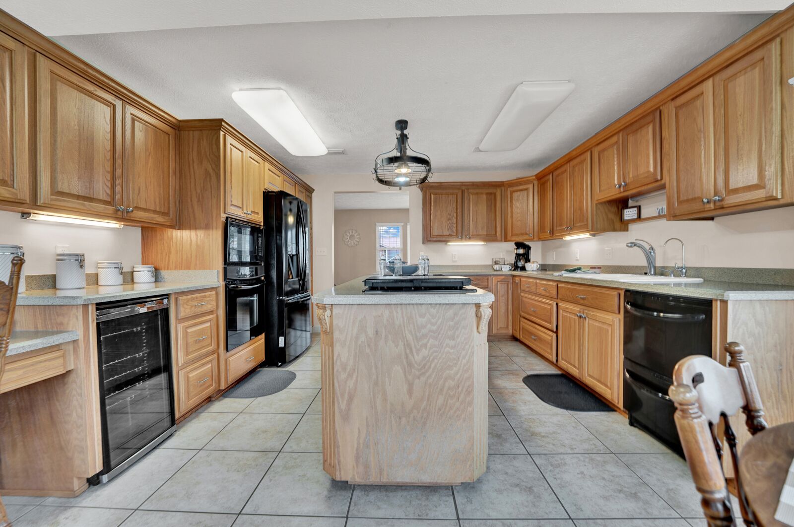 Une cuisine moderne avec des meubles en bois, un îlot central, des appareils en acier inoxydable et un luminaire au plafond.