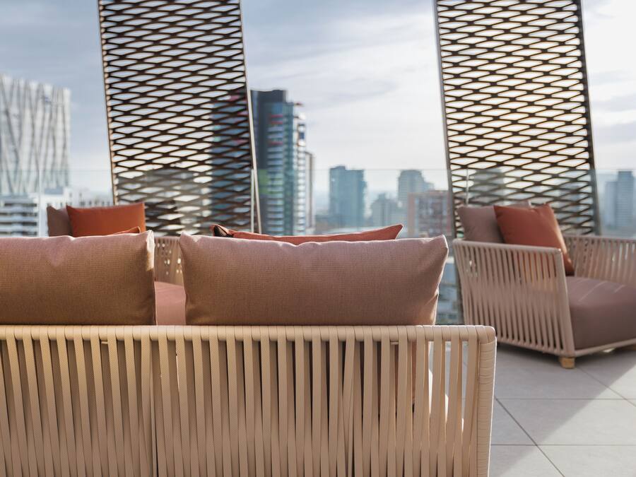 A balcony with wicker furniture and a city view.