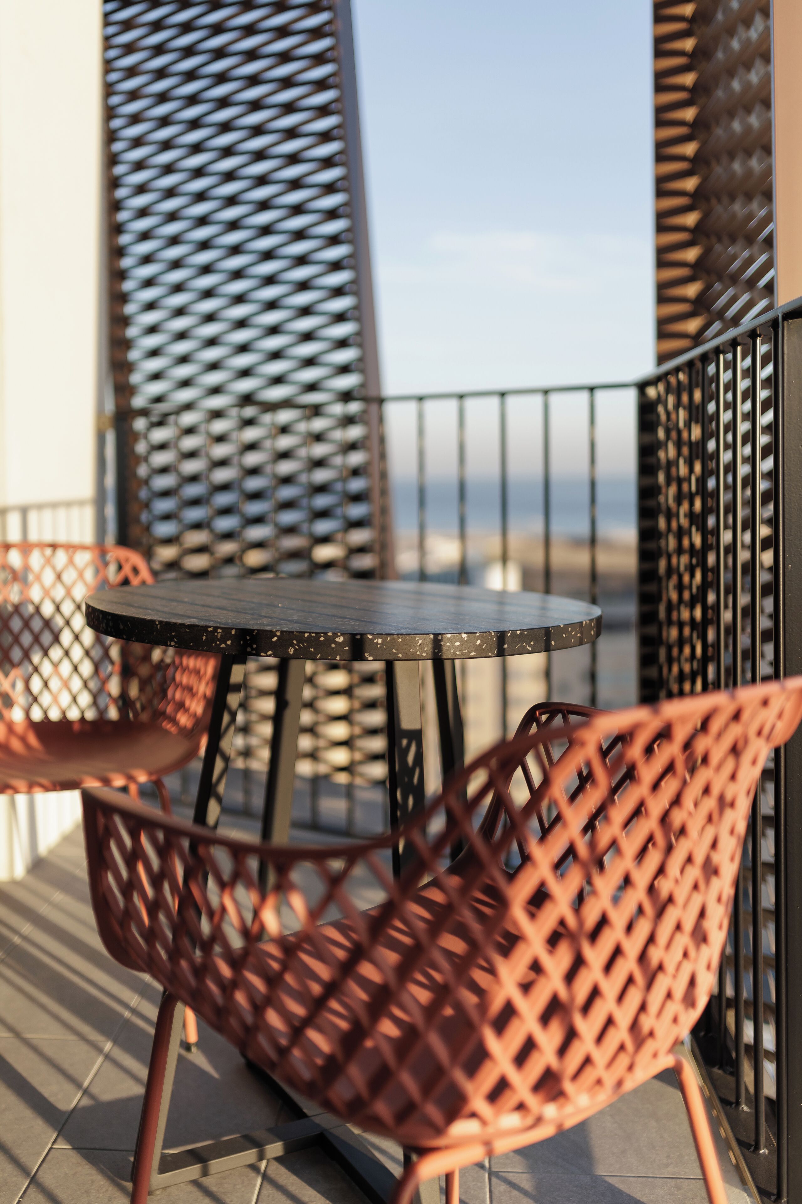 A round table with a metal frame and a single chair with a lattice design.