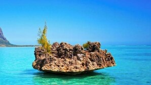 A clear blue sea with a rocky outcrop in the foreground and a mountain in the background. - Villa Floreal 5 (floreal,)