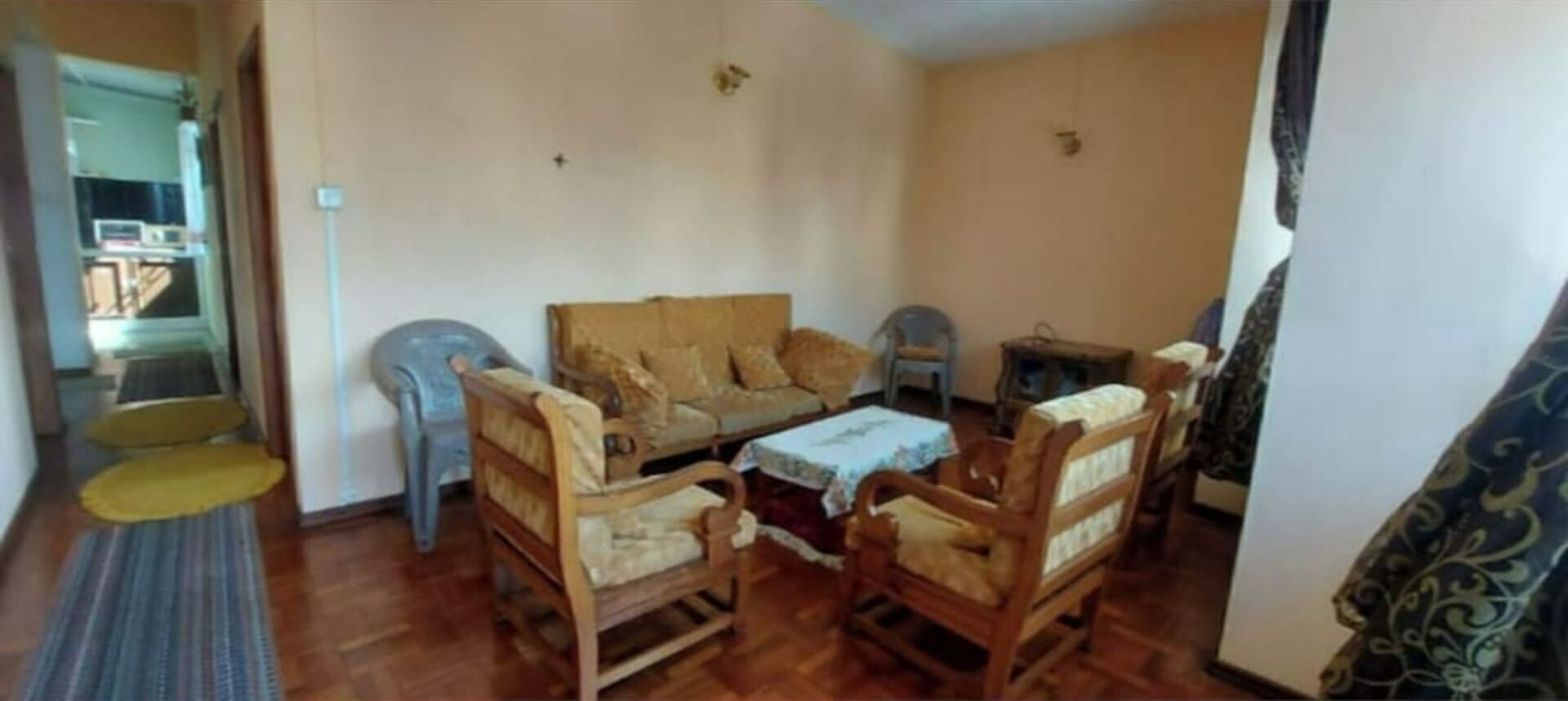Una sala de estar con un sofá, dos sillones, una mesita y una silla de plástico azul.
