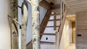 A wooden staircase with a natural tree trunk design, leading to a room with wooden walls and floors.