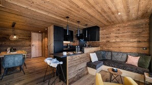 Interior moderno de una cabaña de troncos con comedor, cocina y zona de estar.