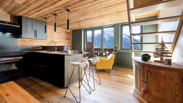 Una cocina moderna con techo de madera, taburetes de bar y vistas a las montañas.