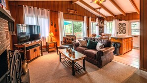 Un salon chaleureux avec une cheminée, un téléviseur et un plafond en bois.
