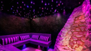 A modern lounge area with a sectional sofa and a stone wall. - N°30 : 4 people mezzanine studio incl. swimmingpool, sauna, hammam (CHAMPAGNY EN VANOISE)