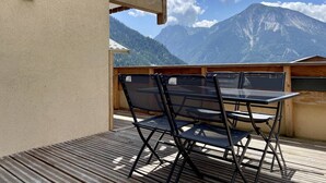 Ein Sitzbereich im Freien mit Tisch und Stühlen mit Blick auf ein Gebirge.