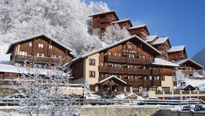Ein mehrstöckiges Hotel mit Blick auf ein Skigebiet, mit einem gut sichtbaren Schild mit der Aufschrift "Club Alpina".