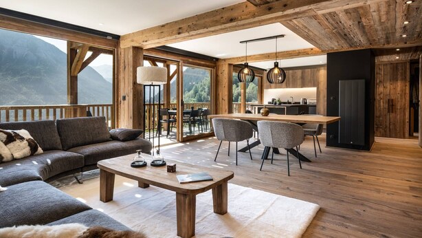 A spacious living area with a wooden ceiling, a sofa, a coffee table, and a dining area with chairs and a table.