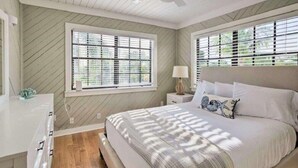 Une chambre à coucher avec un lit, des tables de chevet et une fenêtre avec des stores.