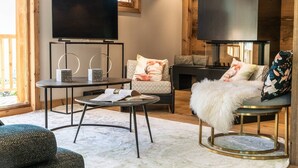 A modern living room with a large flat-screen TV, a round coffee table, and comfortable seating.