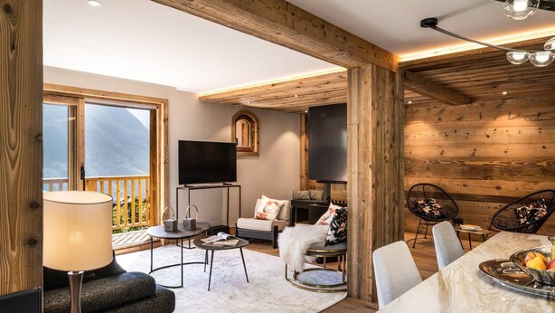 A cozy living room with a fireplace, a television, and a dining area with a table set for two.