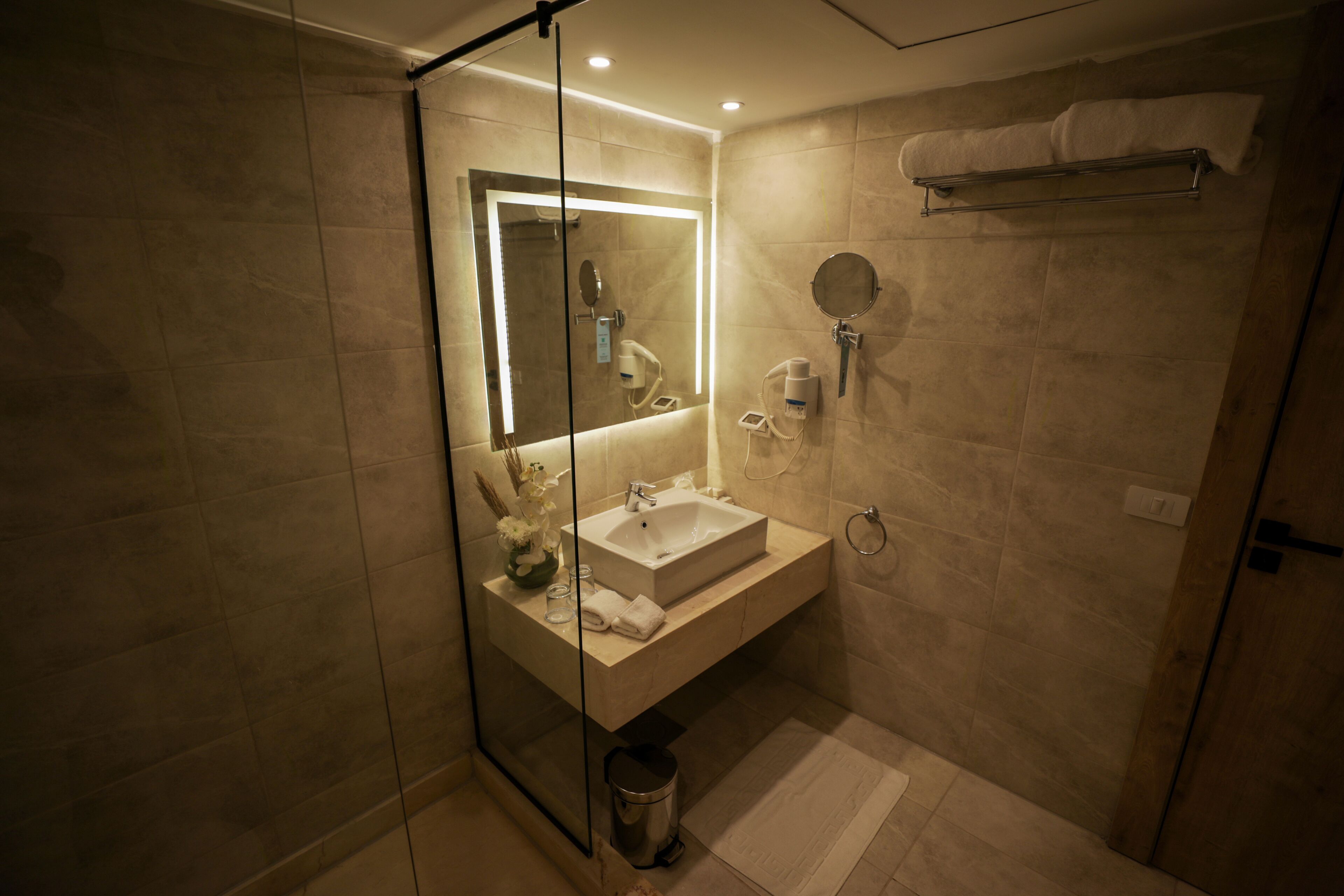 Une salle de bain moderne avec une douche à parois de verre, un lavabo blanc et un miroir.