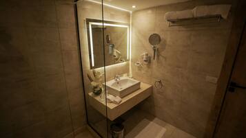 Une salle de bain moderne avec une douche à parois de verre, un lavabo blanc et un miroir.