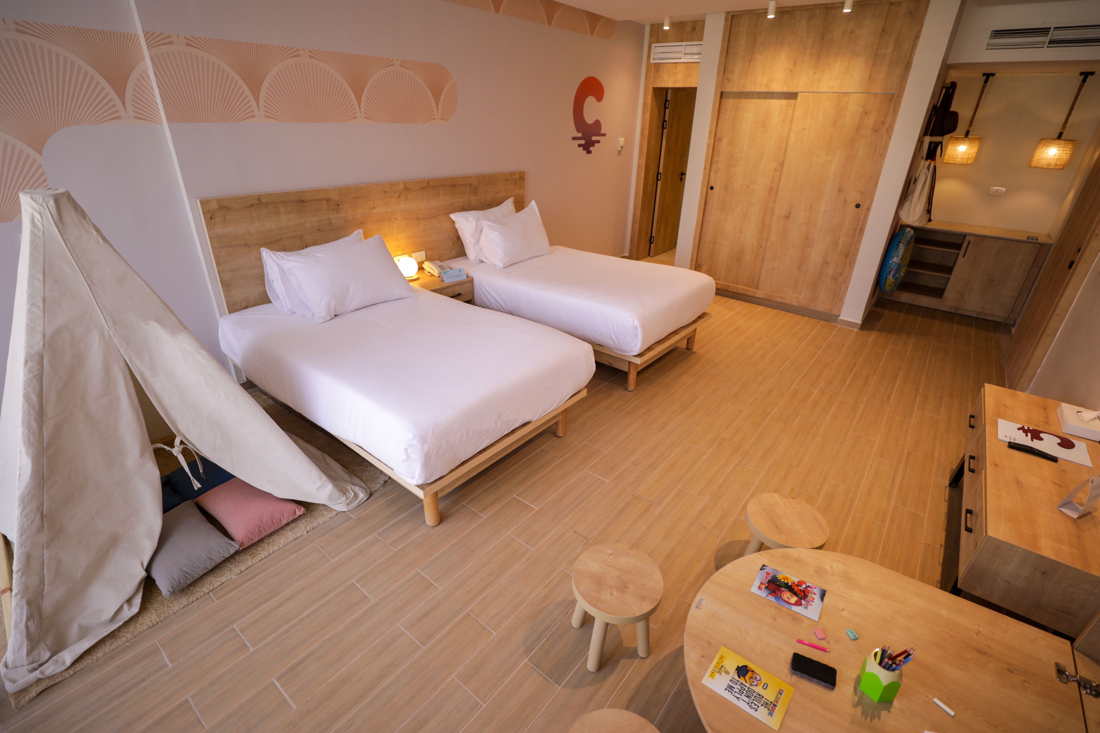 Een hotelkamer met twee bedden, een kleine tafel en een kitchenette.