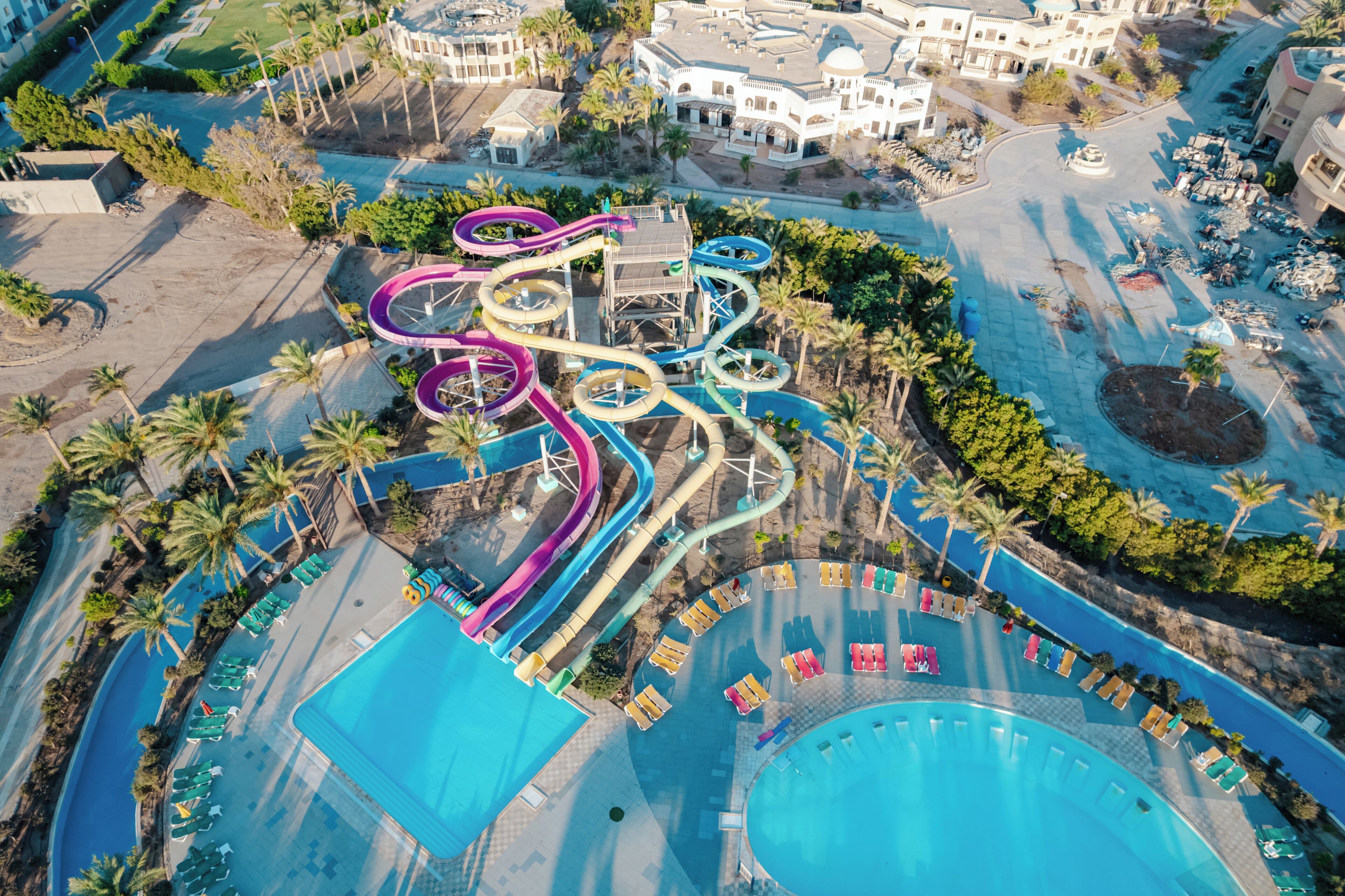 An aerial view of a resort with multiple swimming pools, a water park, and a large building with a dome.