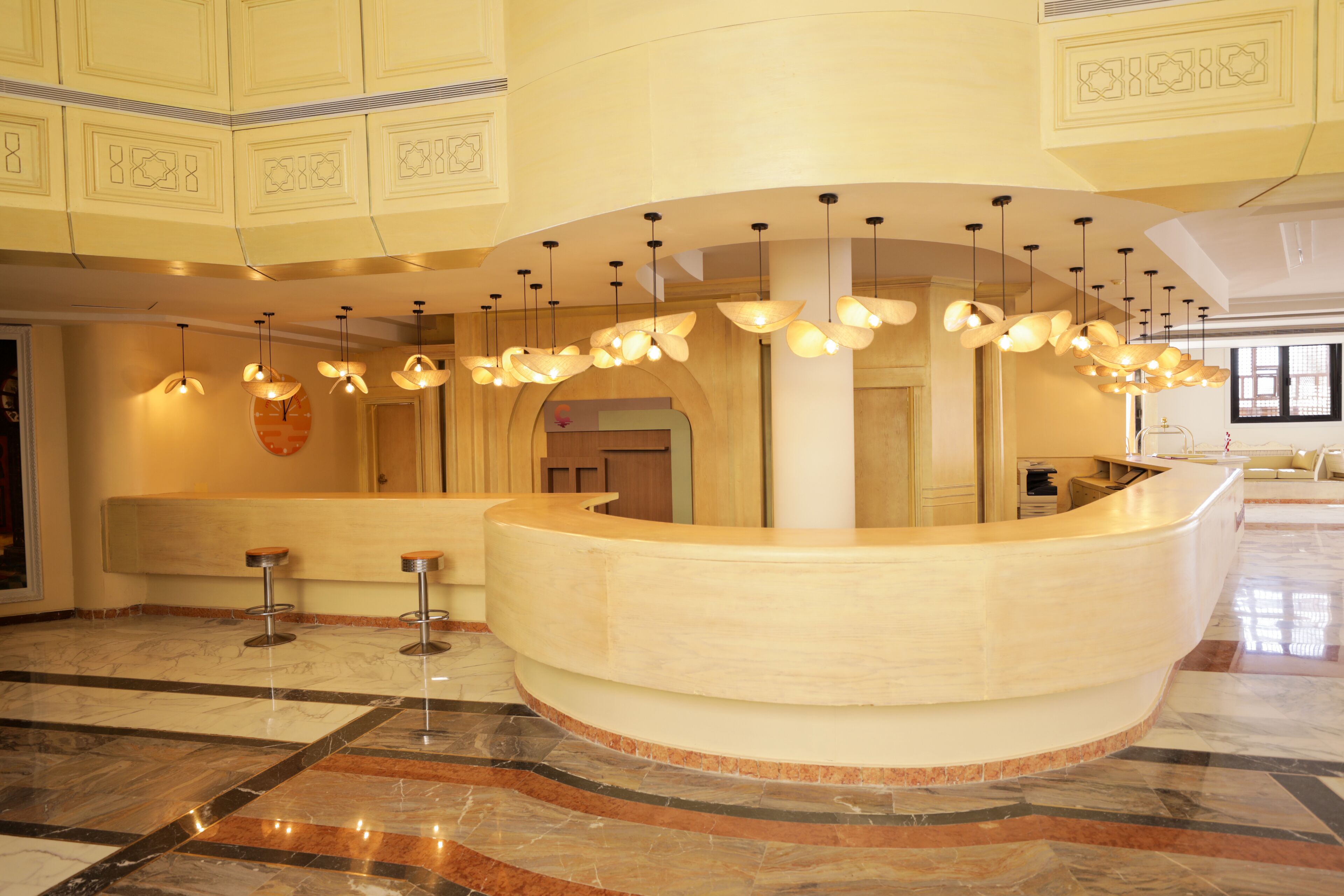 A reception area with a curved counter, multiple hanging pendant lights, and a marble floor.