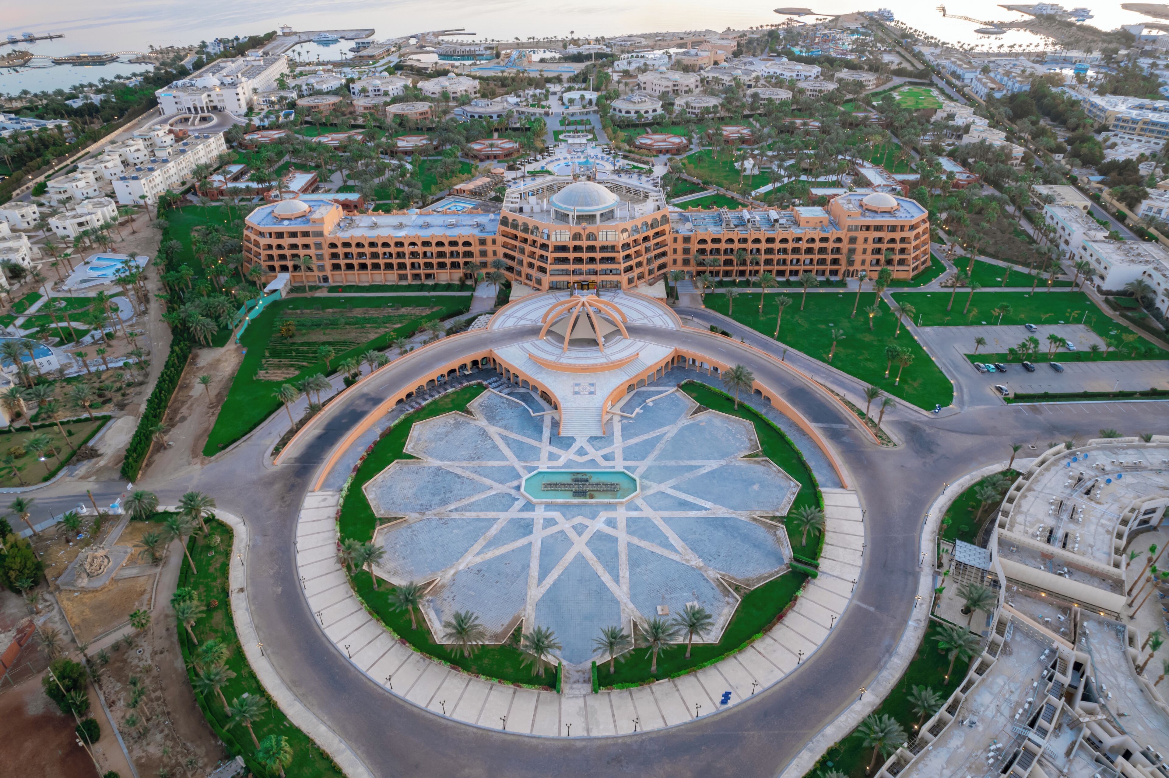 An aerial view of a hotel complex with a central roundabout, multiple buildings, and surrounding greenery.