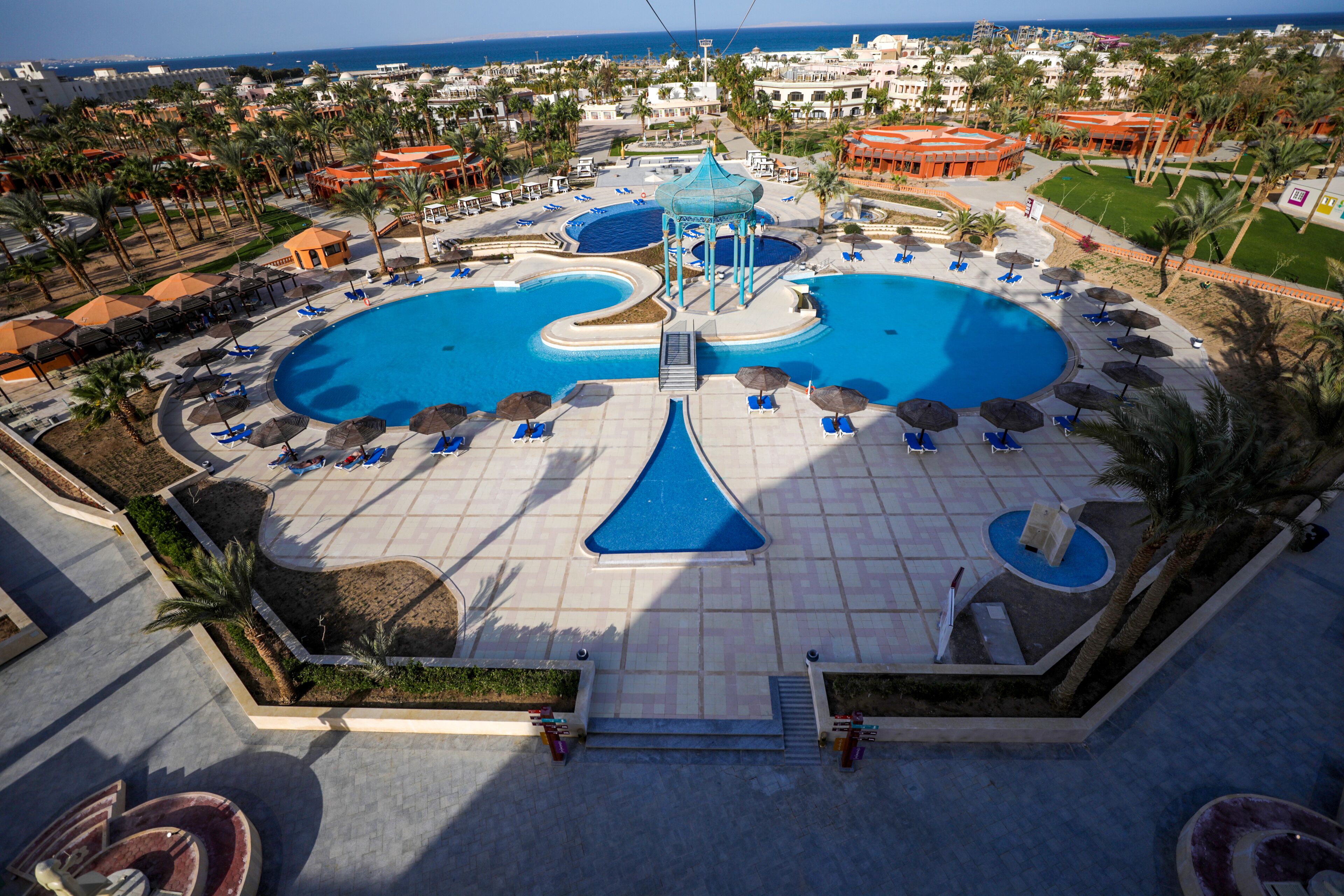 A resort with multiple swimming pools, sun loungers, and palm trees.