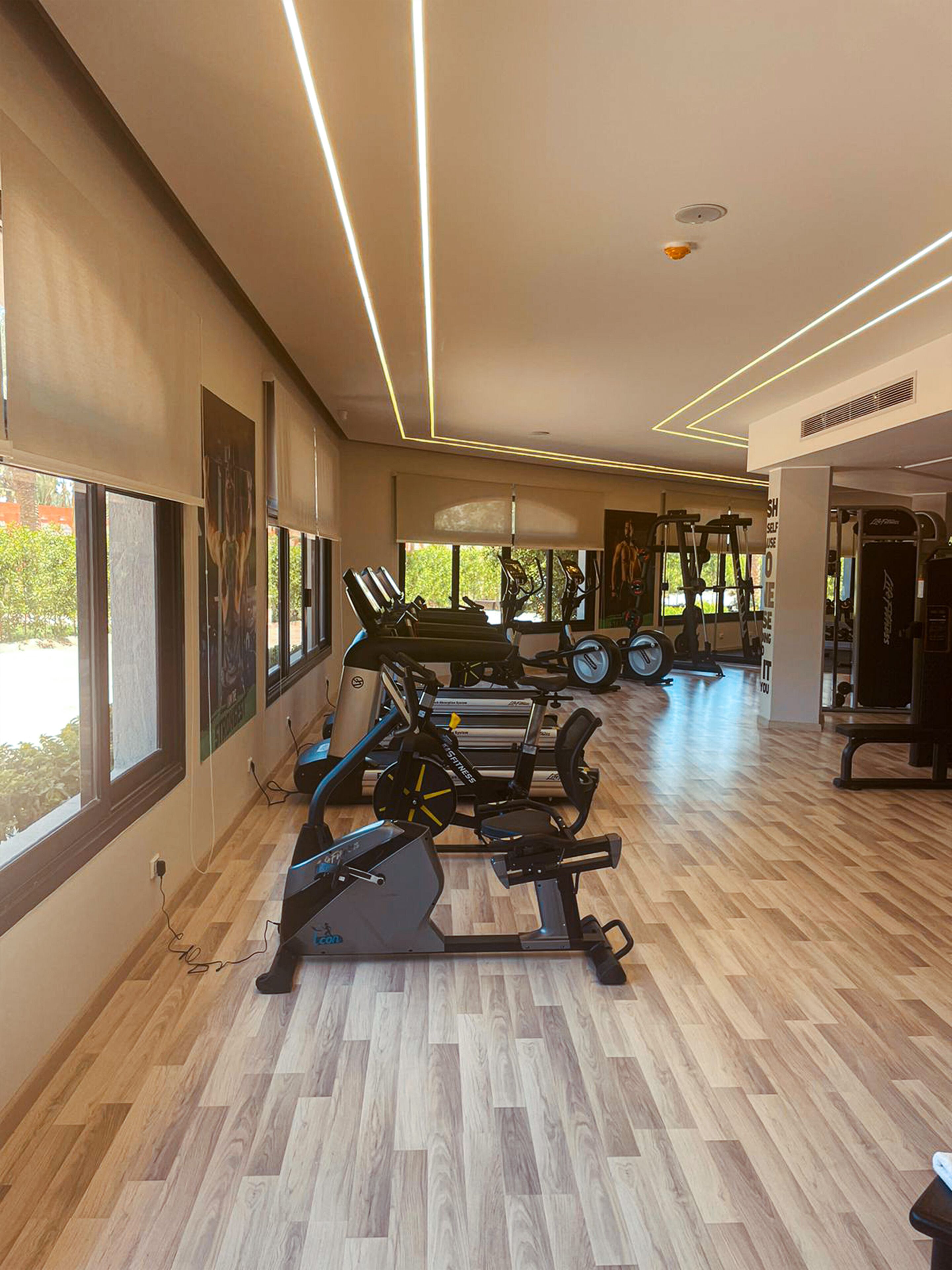 A gym with cardio machines, weightlifting equipment, and large windows allowing natural light.