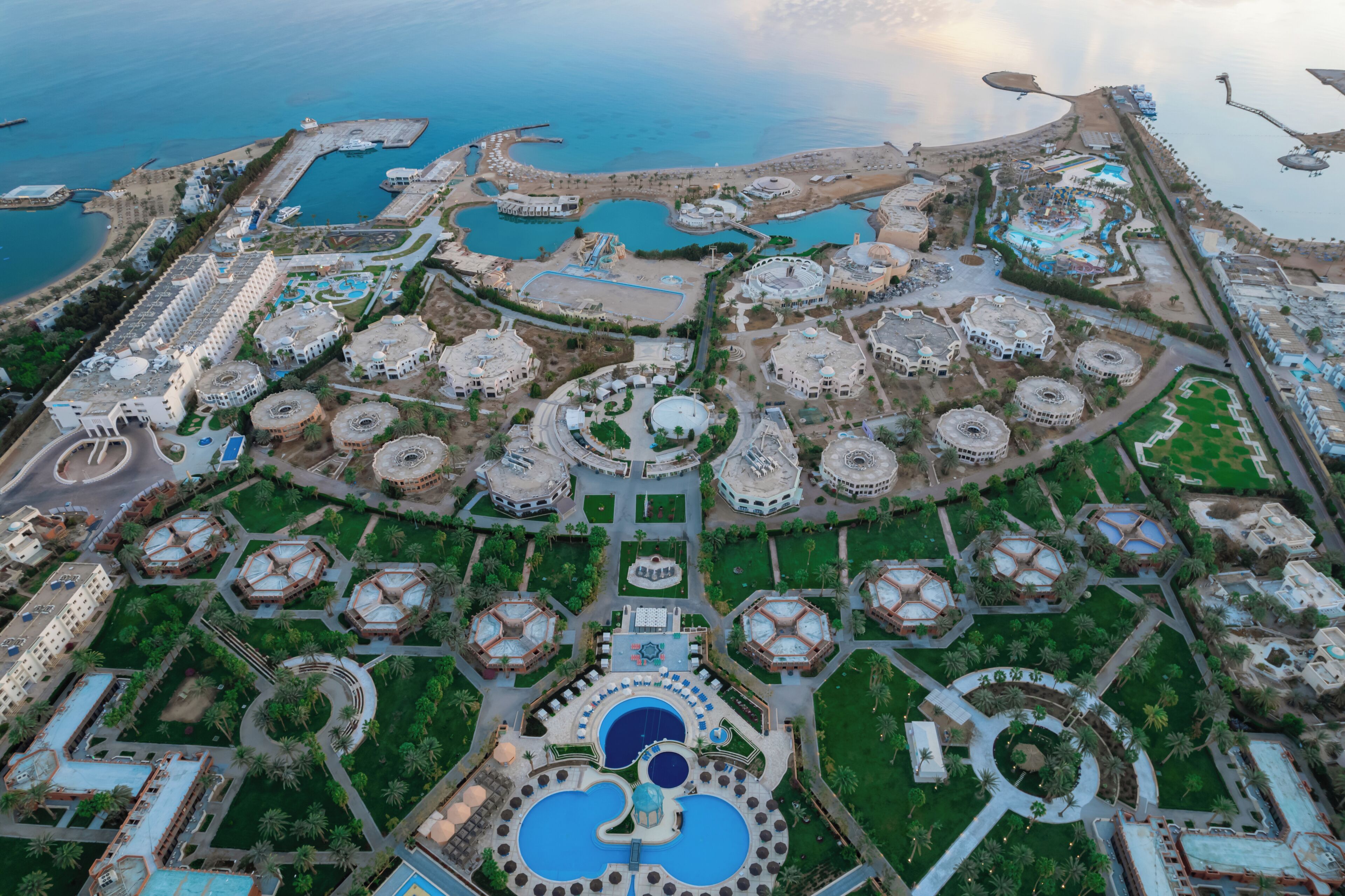 Luchtbeeld van een resort met meerdere ronde gebouwen, een centraal gelegen zwembad en omliggend groen.