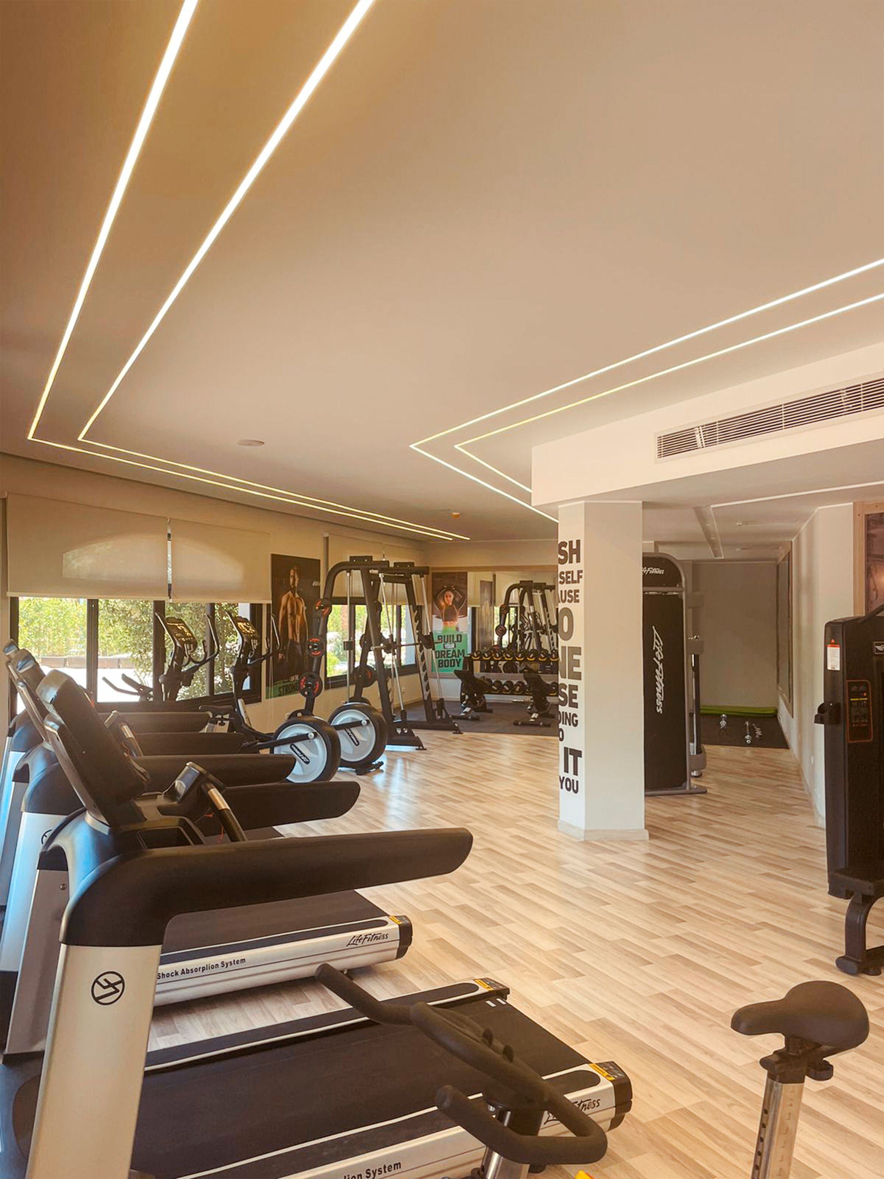 A modern gym with treadmills, elliptical machines, and weight equipment.
