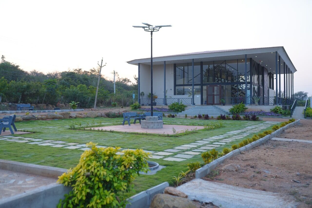 A modern building with a glass facade, surrounded by a well-maintained garden with pathways and seating areas.