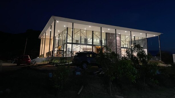 A modern building with large glass windows and a flat roof. - Bliss Farm Stay-JASMINE (Amangal)