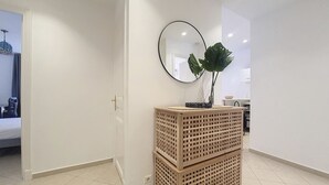 A hallway with a wooden crate stack, a round mirror, and a potted plant. - N&J - JACARANDA- Central, very close sea (Niza)