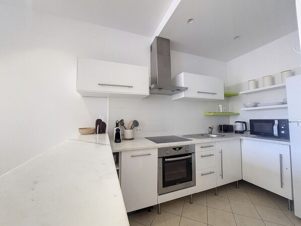 A modern kitchen with white cabinets, a stainless steel oven, a microwave, and a sink. - N&J - JACARANDA- Central, very close sea (Niza)