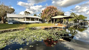 A house with a deck and a gazebo by a pond with lily pads. - House on Canal access to Lake! (Okeechobee)