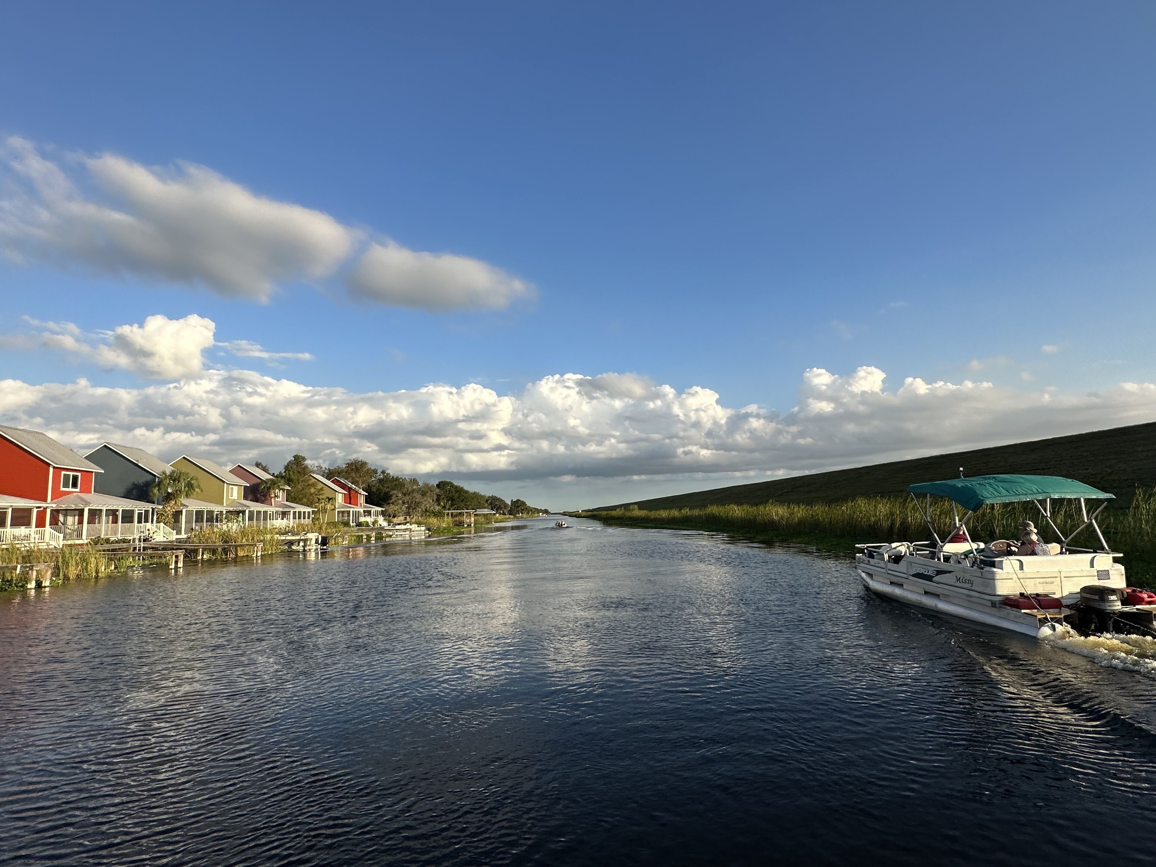 A canal with houses on one side and a boat on the other.