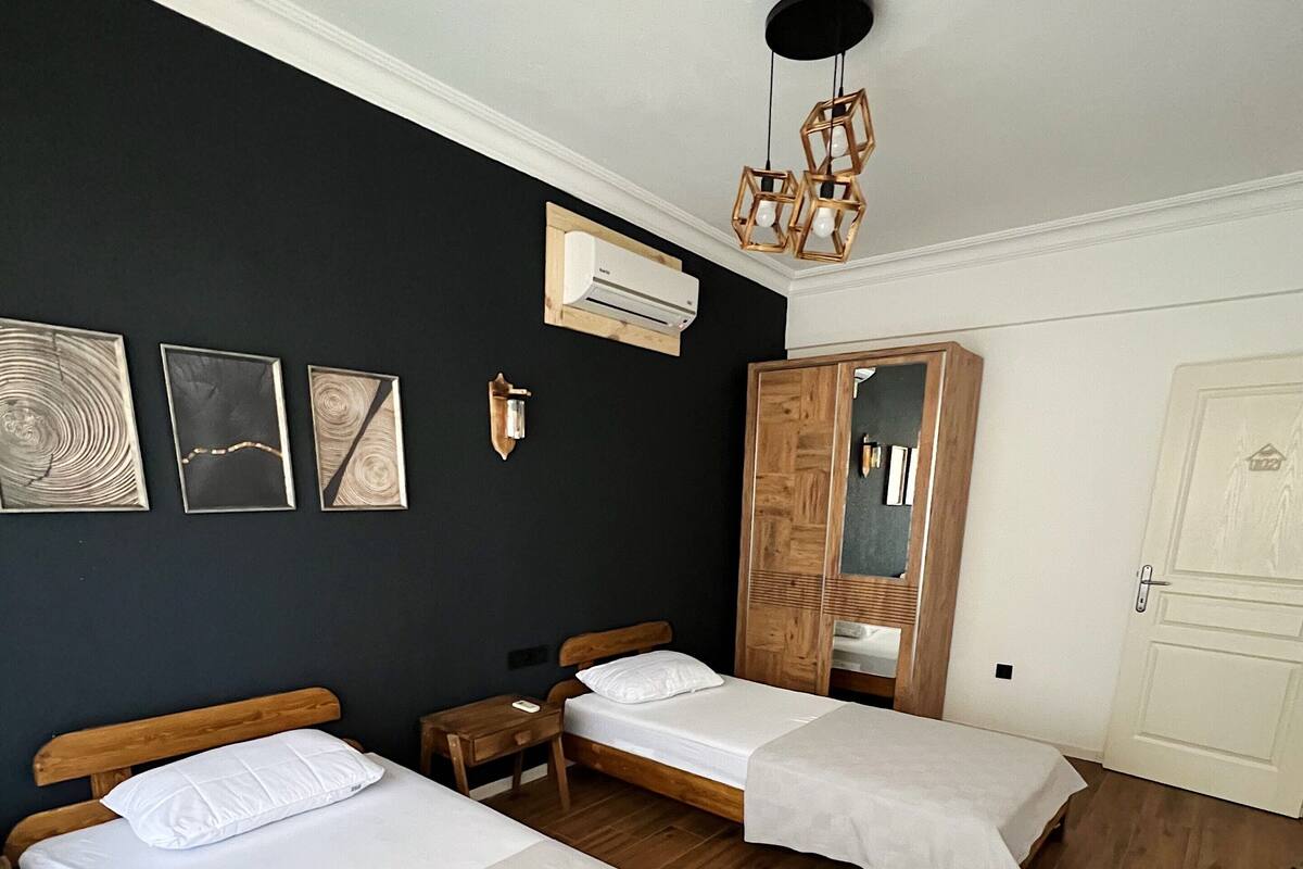 Una habitación con dos camas de madera, un armario, un espejo y una lámpara en el techo.