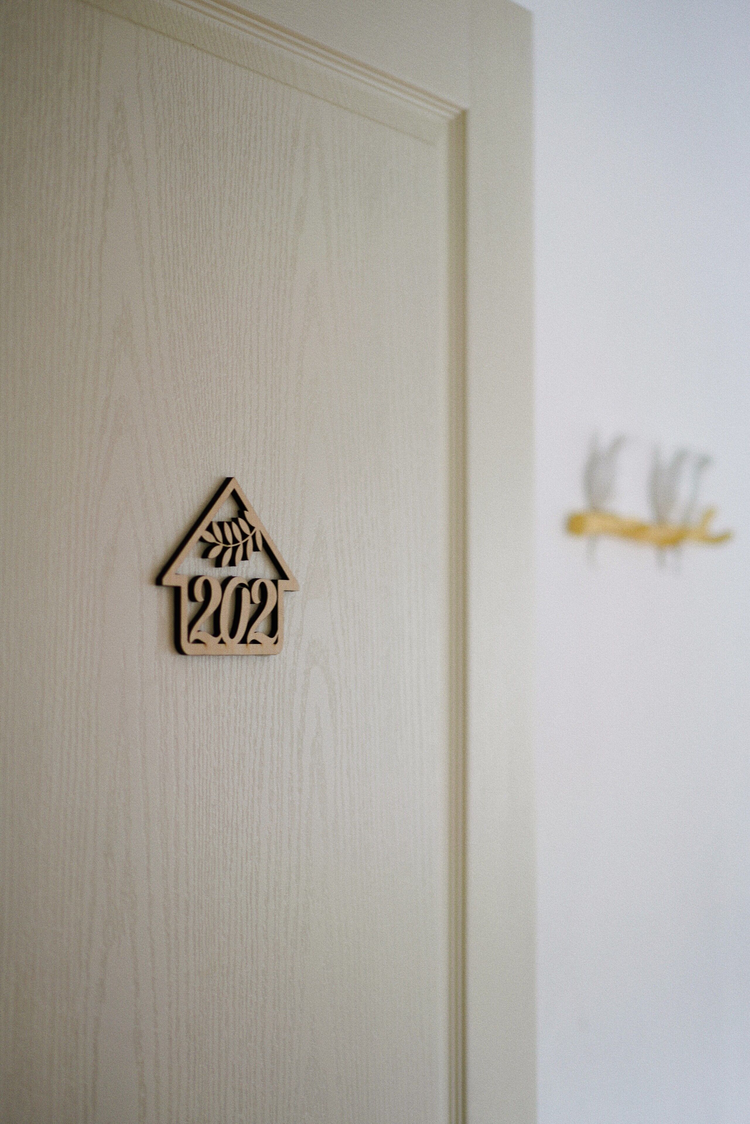 A wooden house-shaped plaque with the number 2022 on a door.