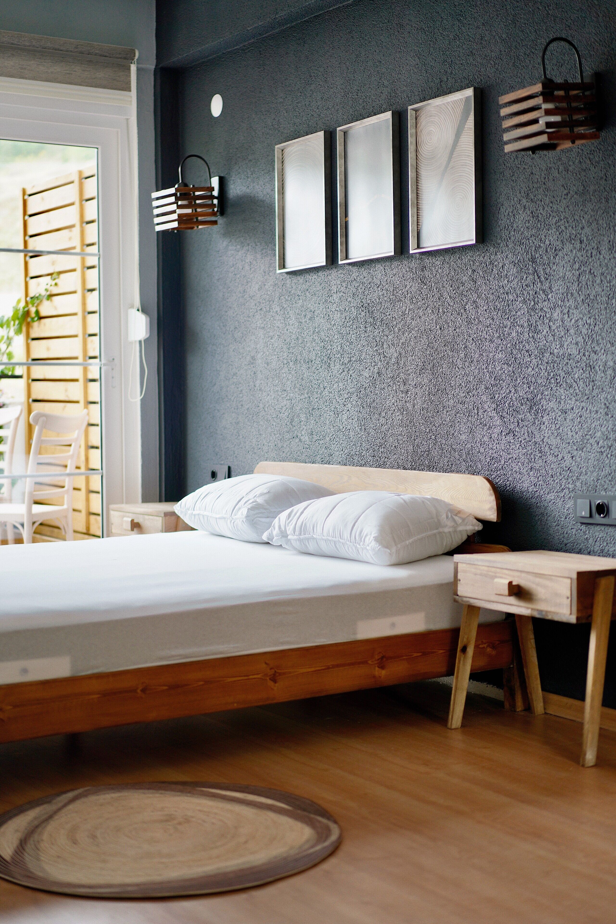 Ein modernes Schlafzimmer mit einem Bett, Nachttischen, Holzboden und einer Wand mit Grau-Struktur.