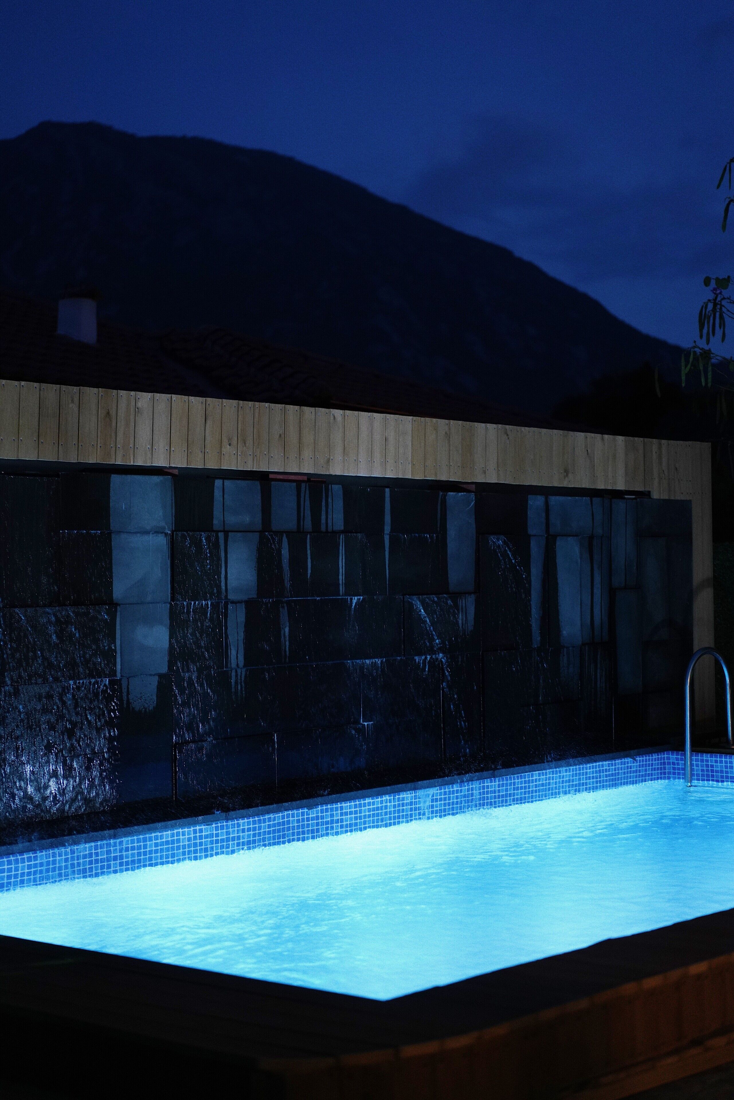Una piscina con borde de azulejos y zona de cubierta de madera.