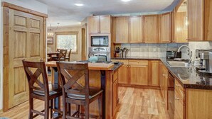 A kitchen with wooden cabinets, a dining table with chairs, a stove, and a sink. - Ziggy Bear Lodge (Breckenridge)